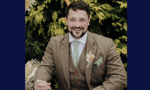 A photograph of Simon Blundell wearing a brown suit