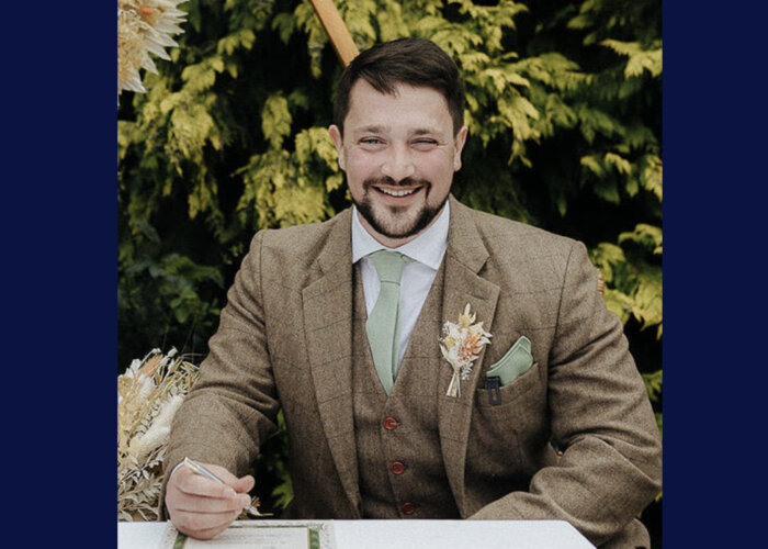 A photograph of Simon Blundell wearing a brown suit